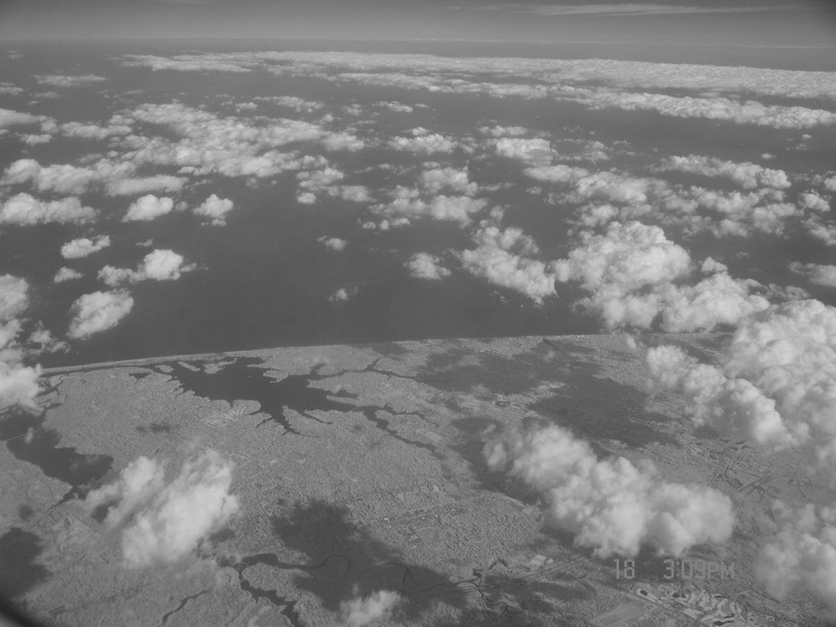 Photo of the same clouds, land, lakes, and ocean but using a near infrared camera.