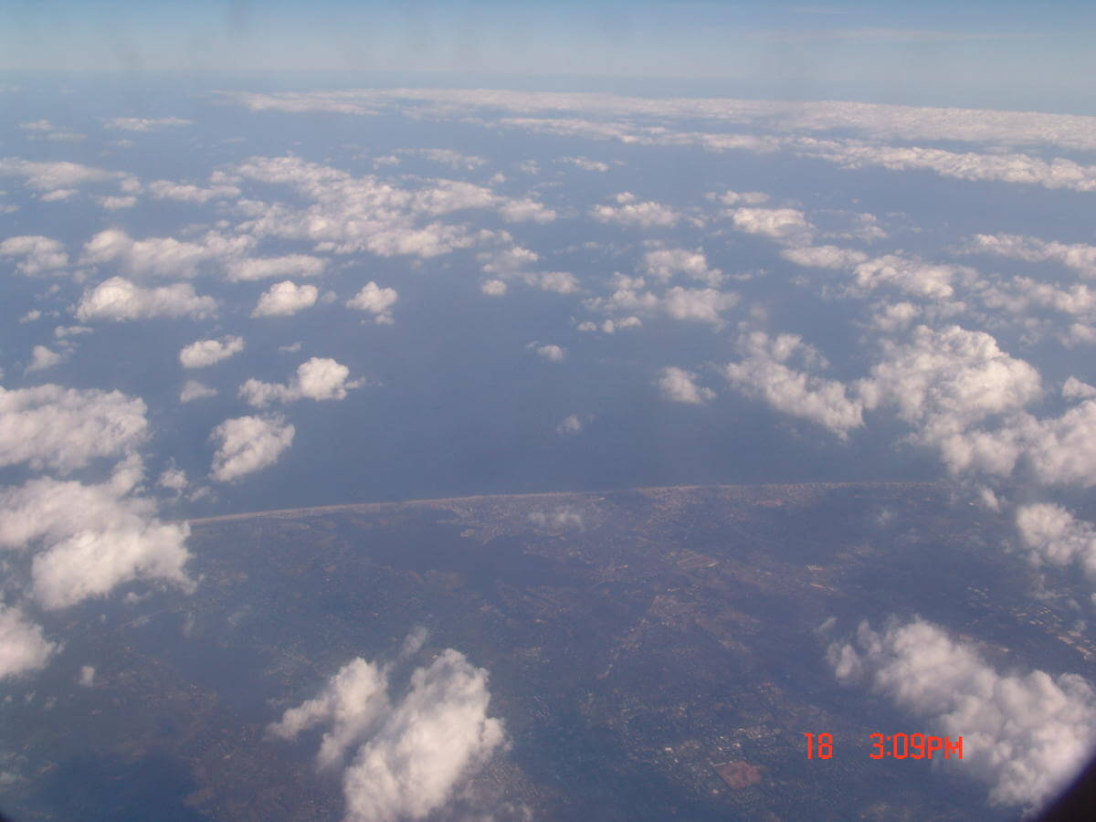 Photo of clouds, land, lakes, and ocean taken from an airplane .