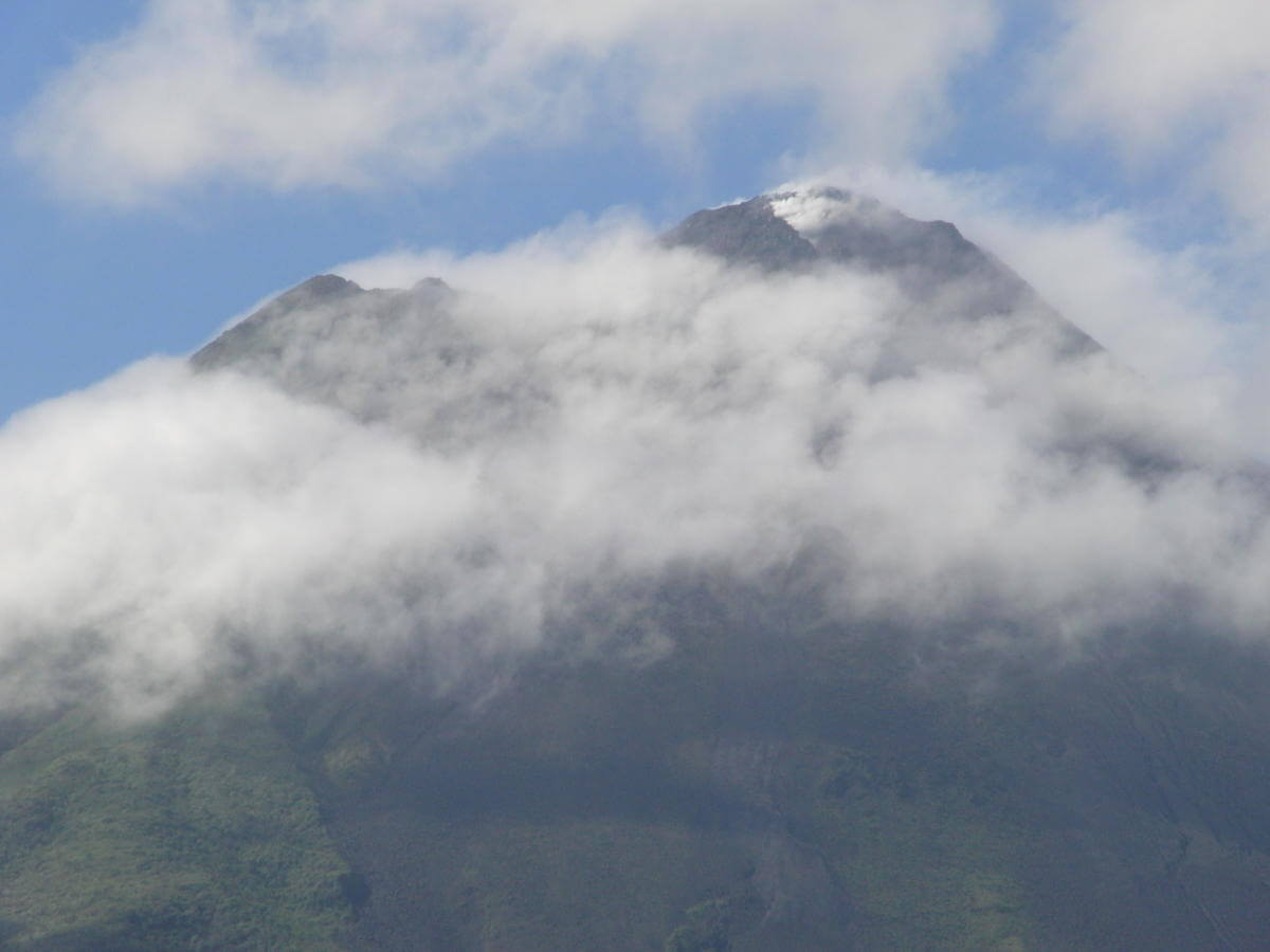 Photo of clouds at the top of a mountain.