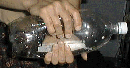 Photo of squeezing a sealed 2-liter soda bottle with an LCD thermometer inside.